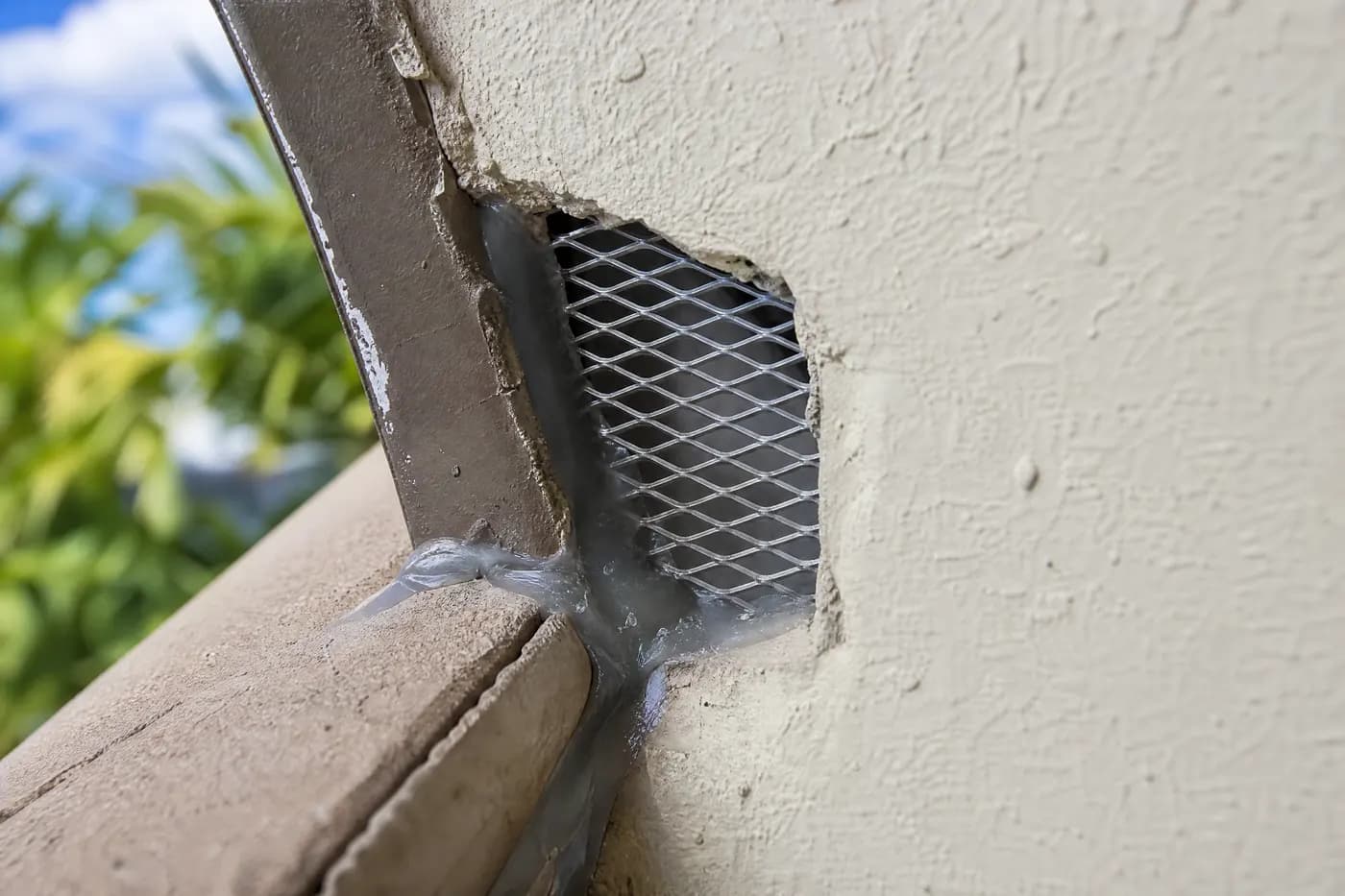 A gap at a stucco roof return closed with steel mesh bedded in sealant against stucco