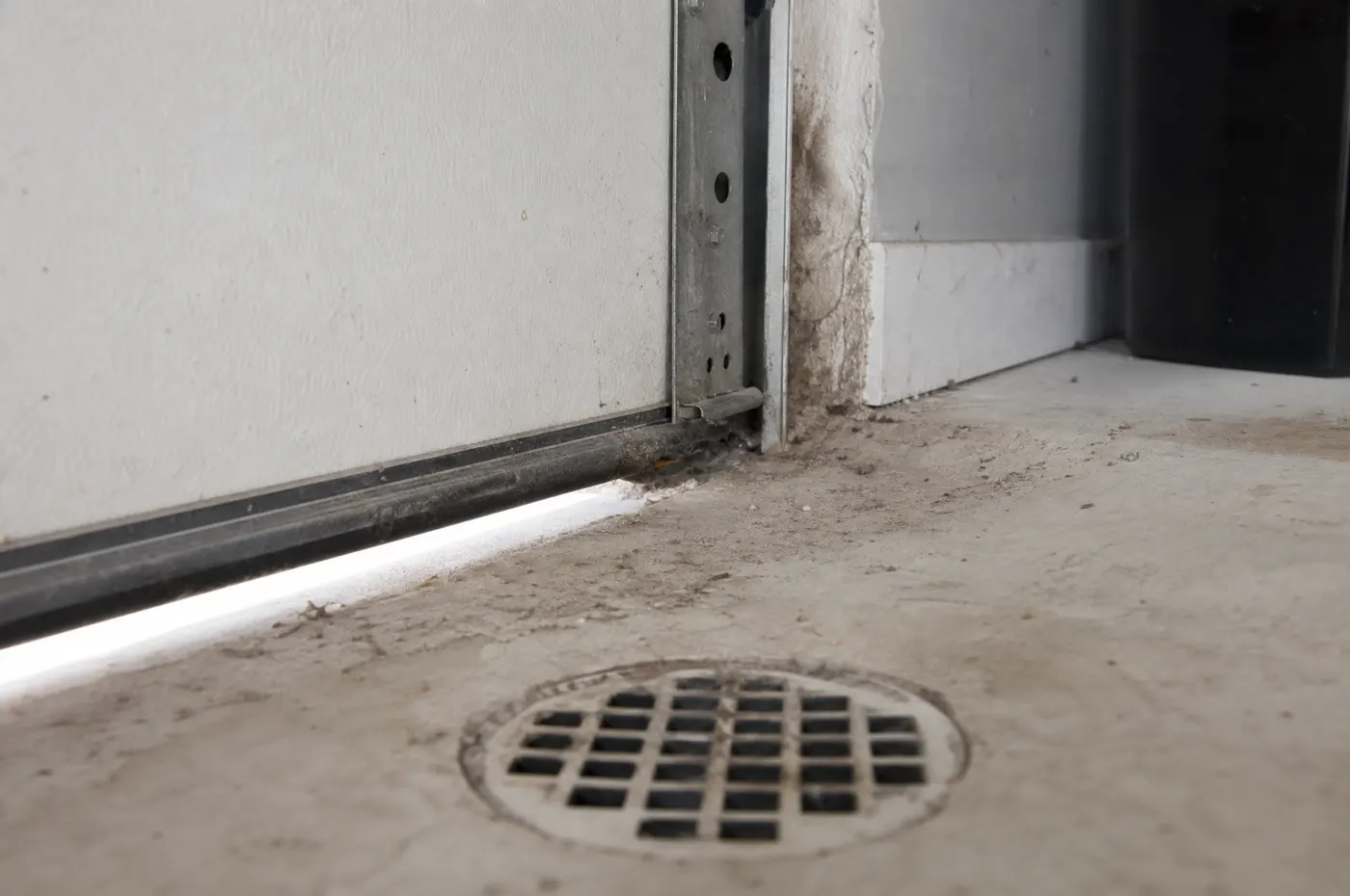 Garage door sweep and floor drain showing exclusion points for a large outdoor cockroach